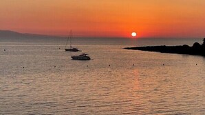 A sunset over a calm sea with boats and a rocky shoreline. - Beautiful 41 m² with balcony (Antibes)