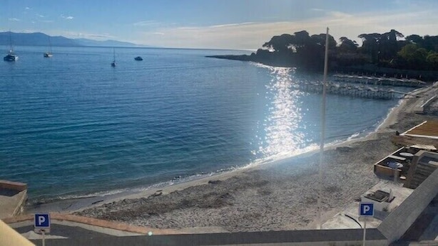 A coastal view with boats on the water, a beach, and parking signs. - Beautiful 41 m² with balcony (Antibes)
