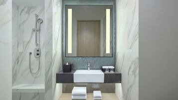 Un baño moderno con ducha de mármol, un espejo grande, un lavamanos y dos toallas en un estante.