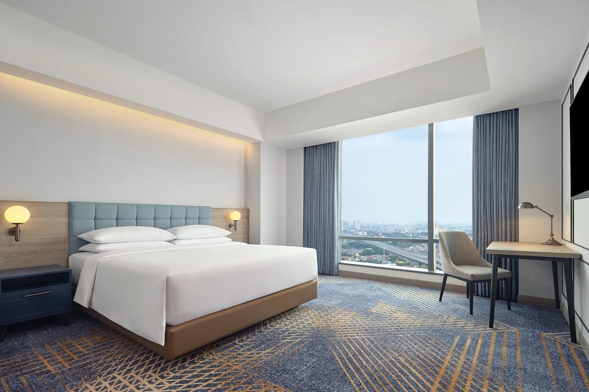 Une chambre d’hôtel moderne avec un grand lit, un bureau et une vue sur la ville.
