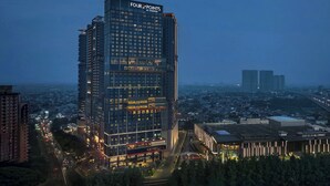 A high-rise hotel with a prominent 'Four Points by Sheraton' sign, surrounded by other buildings and a cityscape. - Four Points By Sheraton Bekasi (Bekasi)