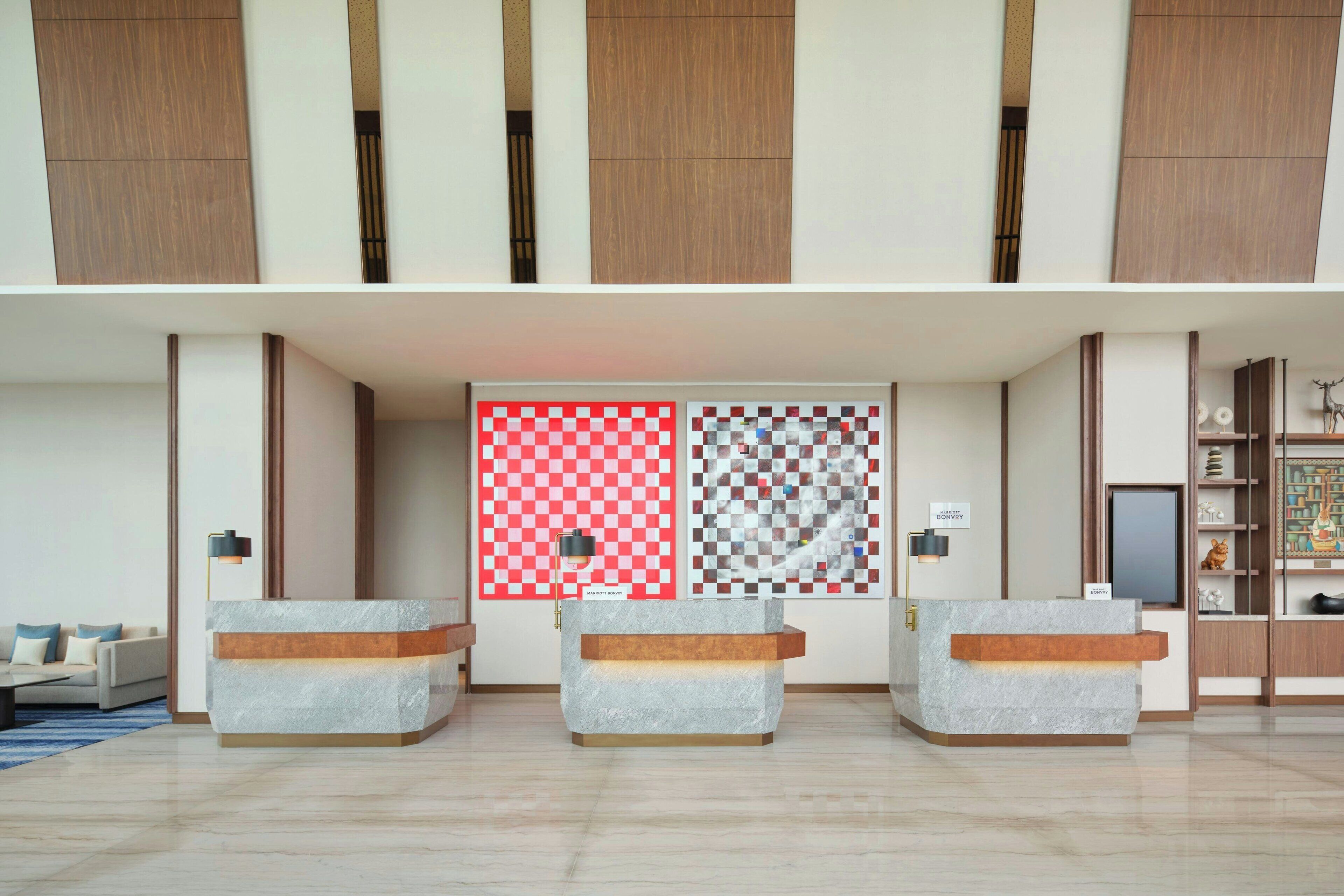 Un área de recepción con un diseño de pared a cuadros, un espacio de espera con sillones acolchados y una exhibición de varios objetos en estanterías.