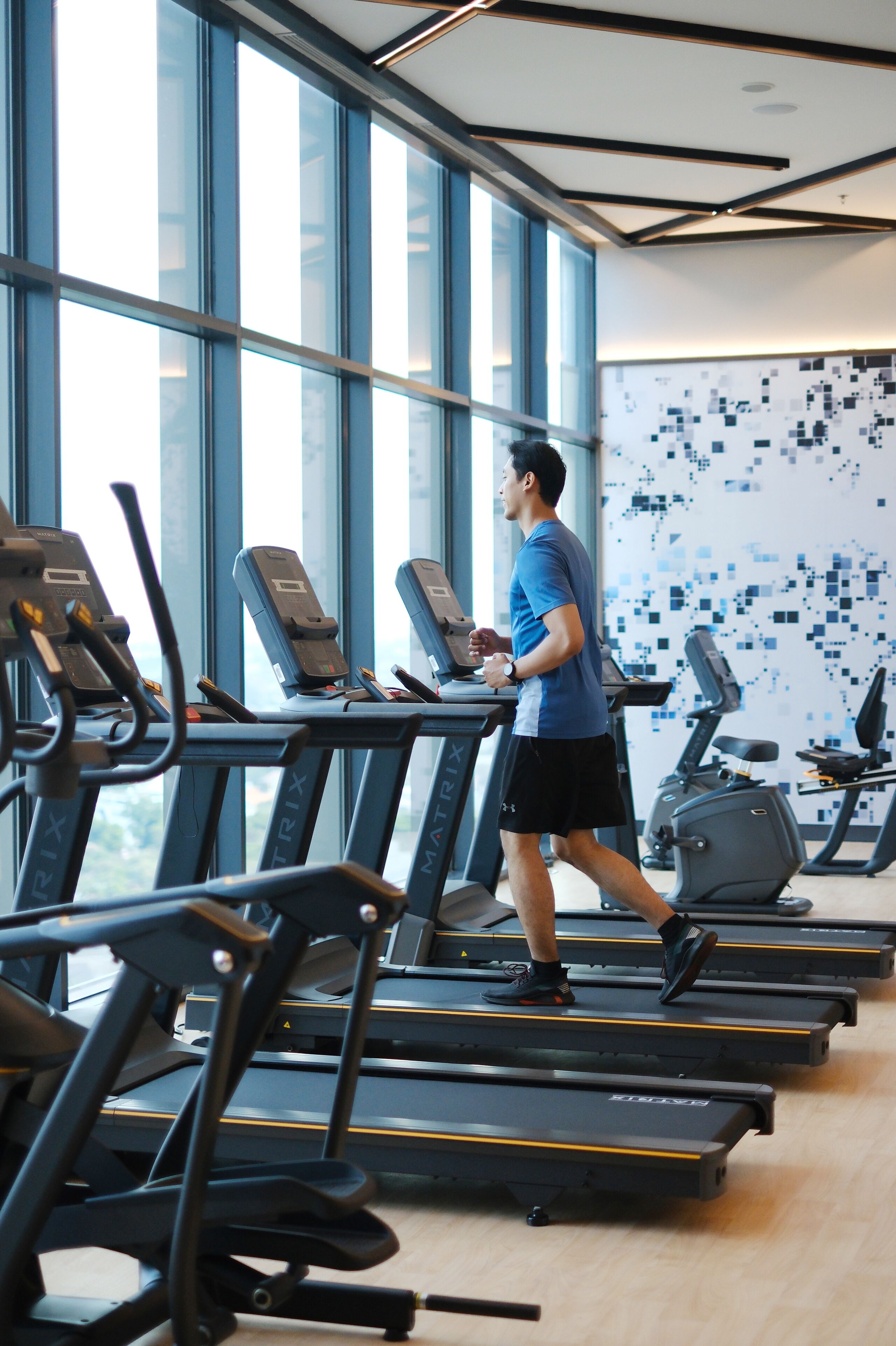 A gym with treadmills and exercise equipment, large windows, and a modern interior design.