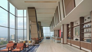 A spacious lobby with high ceilings, large windows offering a city view, a reception desk, and a seating area with sofas and chairs. - Four Points By Sheraton Bekasi (Bekasi)