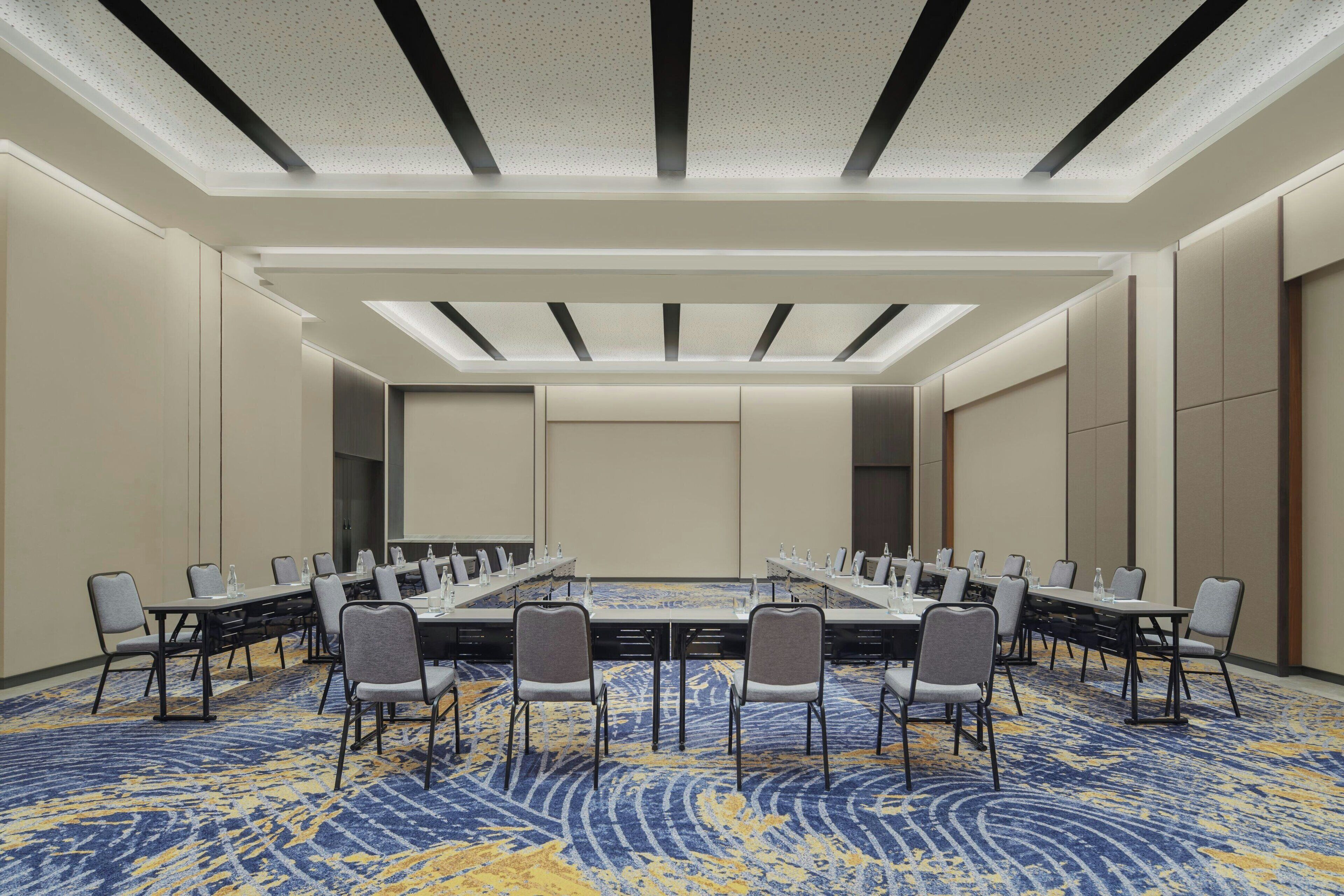 A conference room with a long table, chairs, and a patterned carpet.