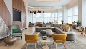 A spacious living area with a sectional sofa, yellow chairs, and a flat-screen TV mounted on the wall. - Element by Marriott Phoenix North Norterra (Phoenix)