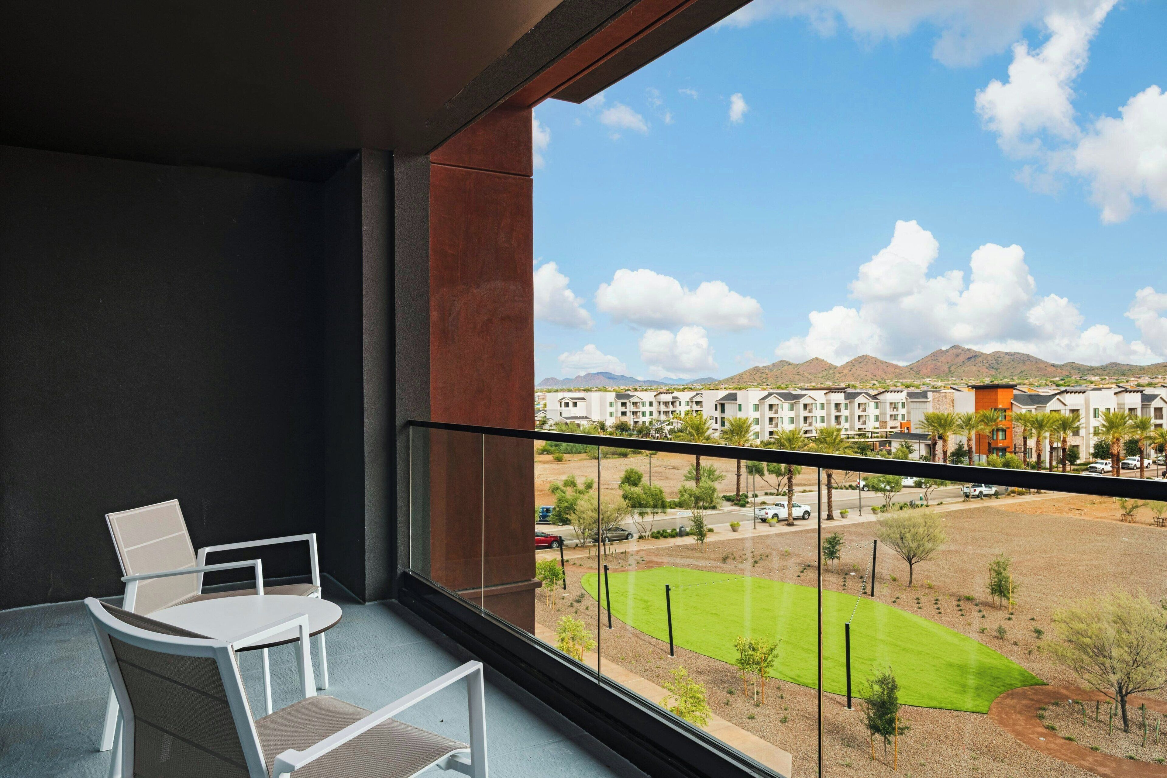 A balcony with a view of a green field and distant mountains.