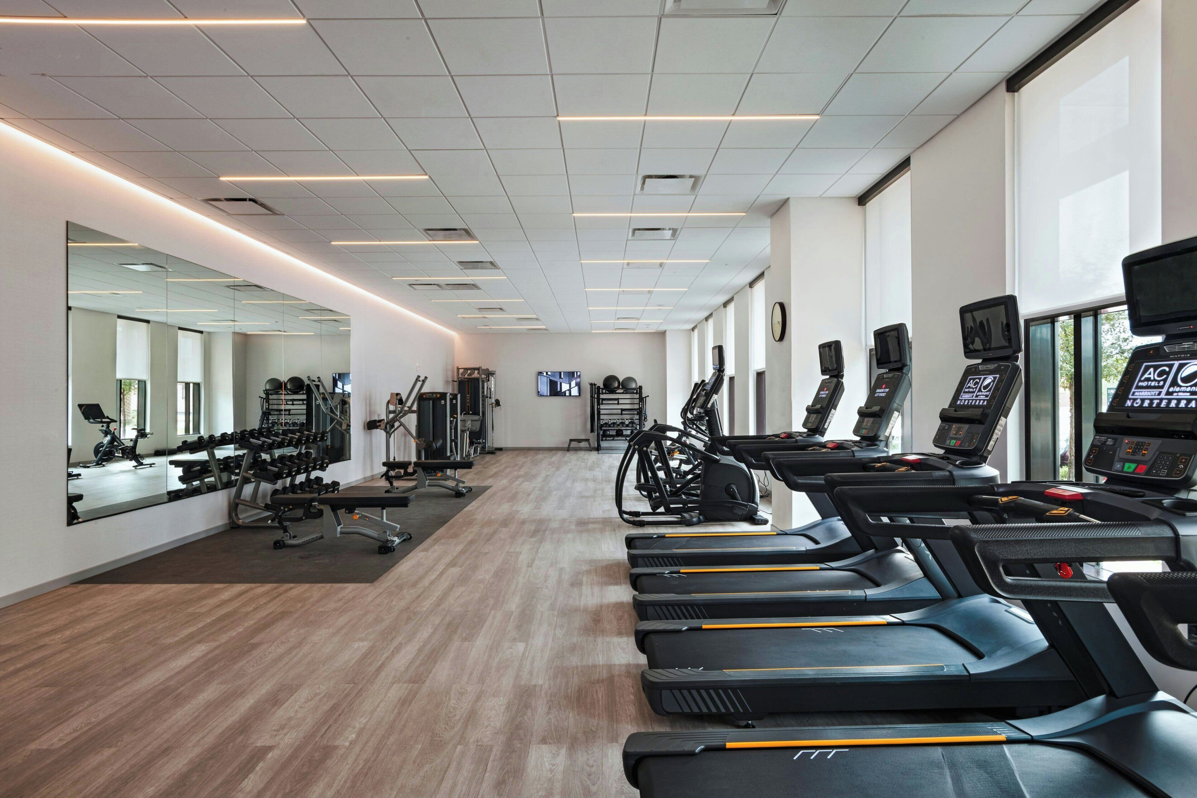 A gym with treadmills, weights, and exercise equipment.