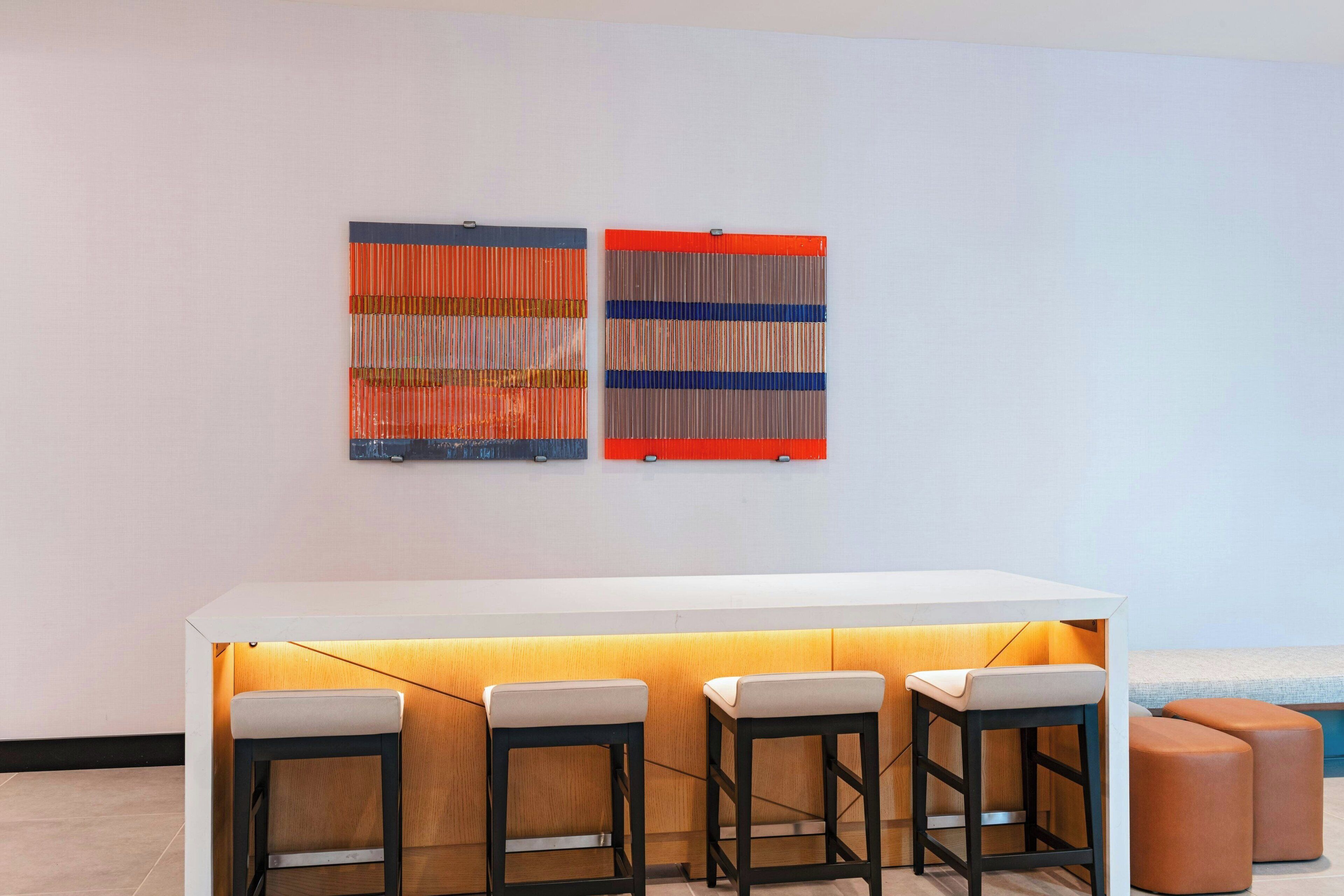 A modern bar area with a white counter and three stools.