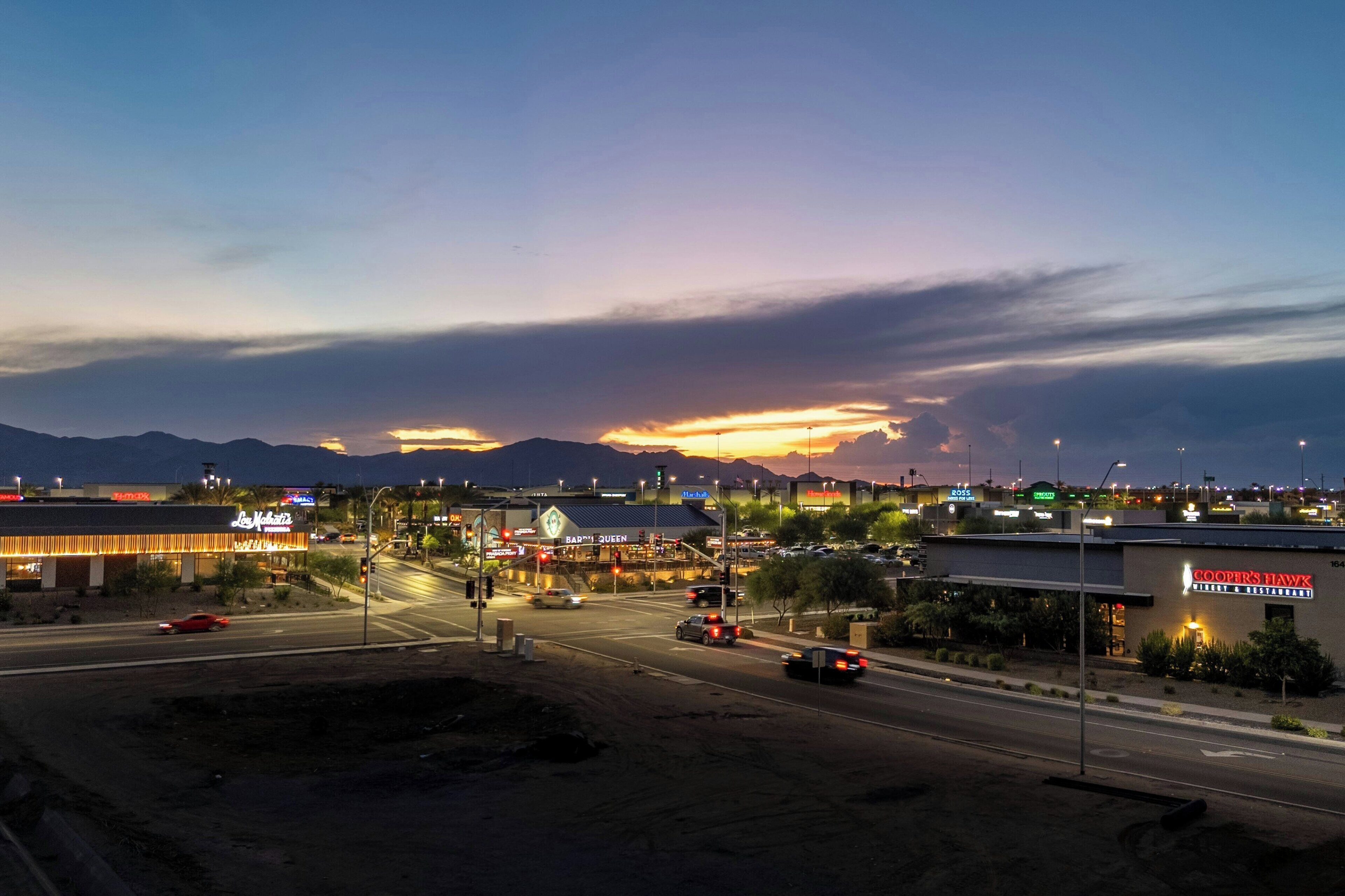 Un paisaje urbano al anochecer, con edificios iluminados y una carretera con vehículos.