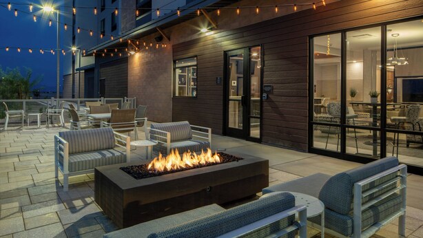 An outdoor patio with seating, a fire feature, and string lights.