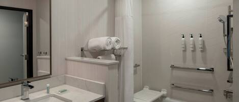 A modern bathroom with a sink, mirror, shower, and towel rack.