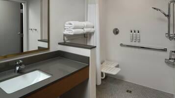Un baño moderno con lavamanos, espejo, toallero, ducha y artículos de aseo.