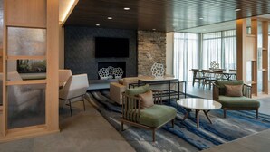 A modern living room with a fireplace, comfortable seating, and a large TV. - Fairfield By Marriott Inn & Suites Foley (Foley)