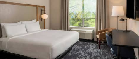 A hotel room with a large bed, a desk, a chair, a TV, and a window with curtains.