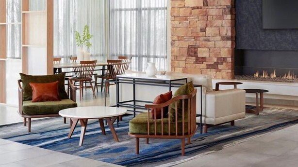 A modern living room with a fireplace, a dining area, and a seating area with a sofa and chairs. - Fairfield By Marriott Inn & Suites Foley (Foley)