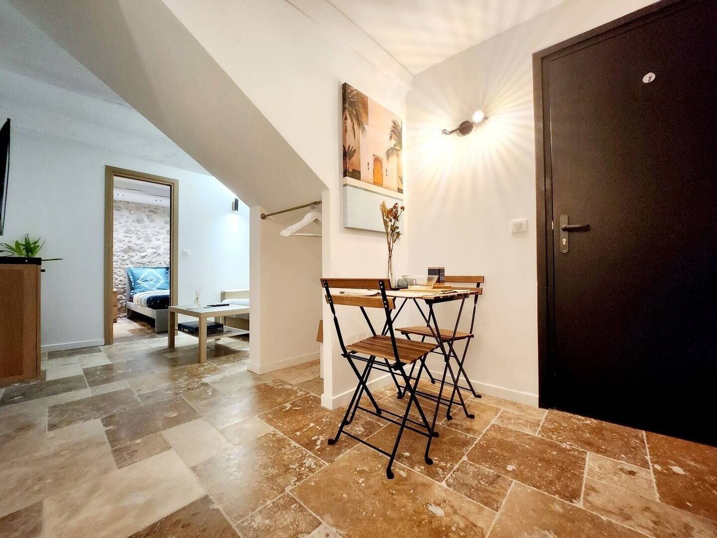 Een eethoek met een tafel, stoelen, een schilderij aan de muur en een deur.