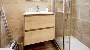 Ein modernes Badezimmer mit Duschkabine aus Glas, Holzwaschtisch und großem Spiegel.