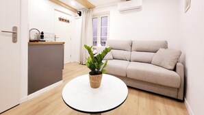Een moderne woonkamer met een ronde witte tafel, een beige bank en een potplant.