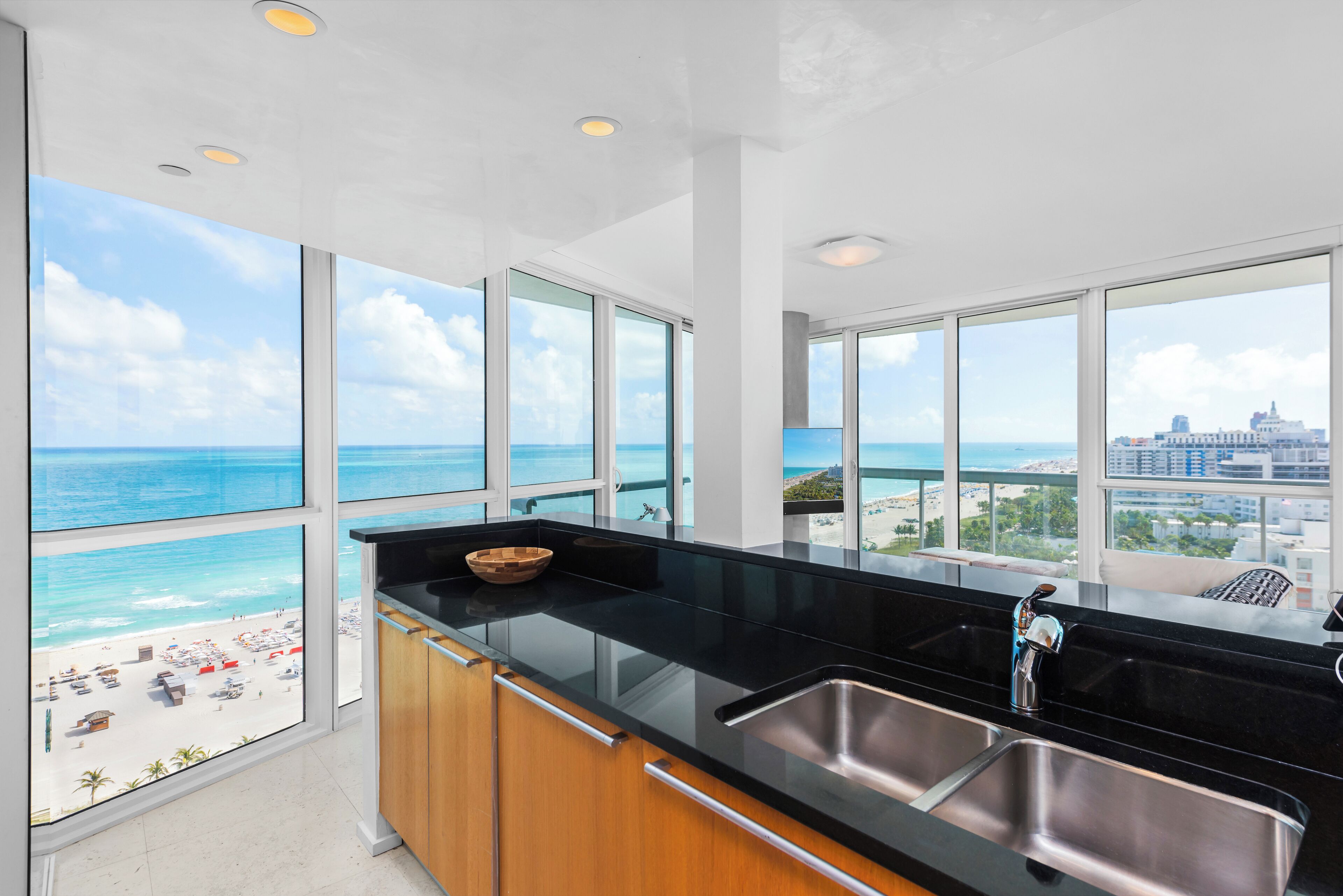 A modern kitchen with large windows offering a view of the beach and ocean.
