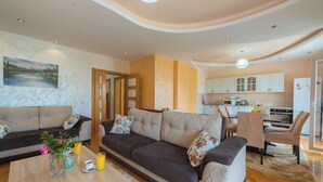 A modern living room with a sofa, coffee table, and a painting on the wall. - Villa Sunny Hill (Budva)
