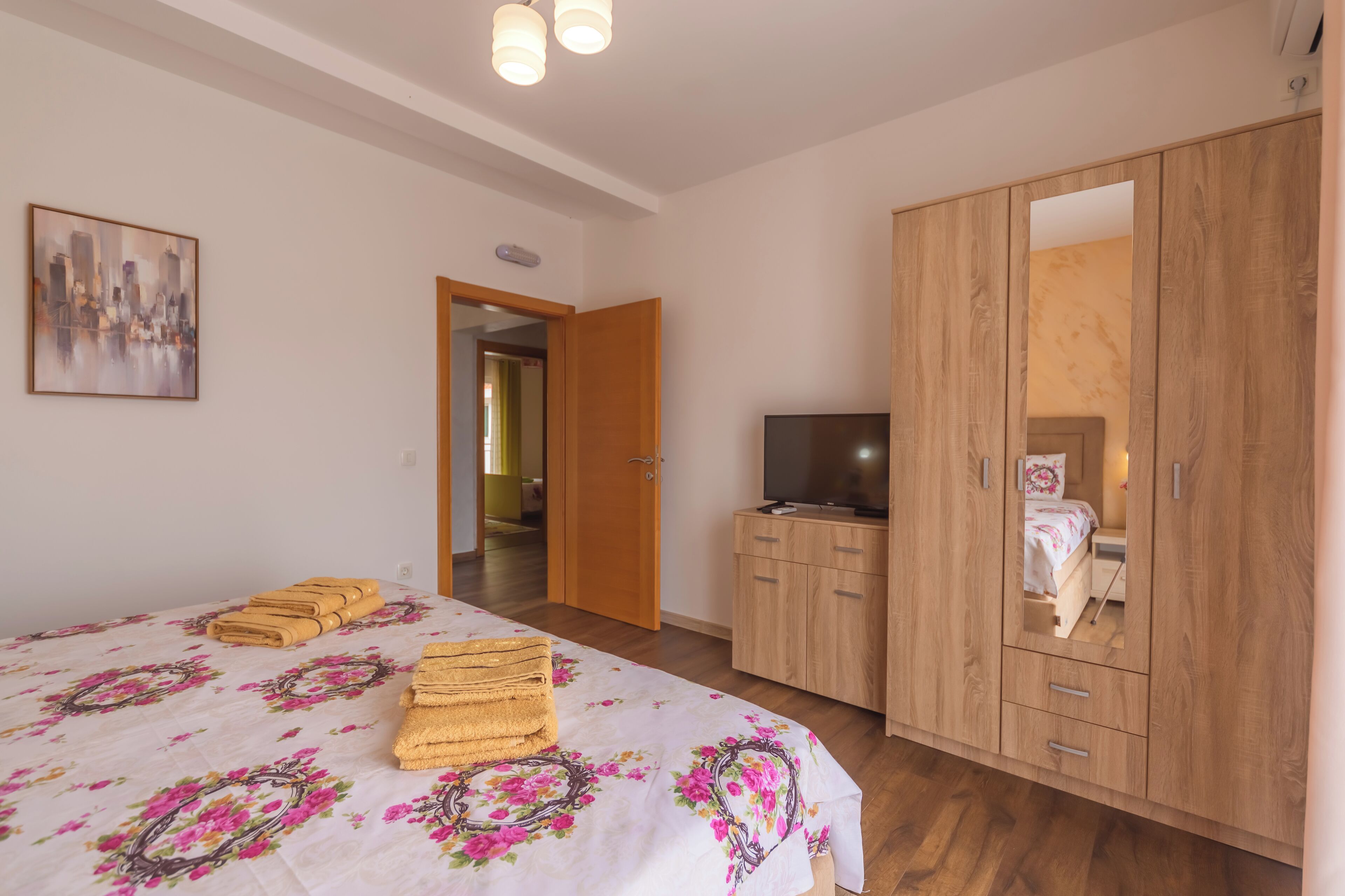 Ein Schlafzimmer mit einem Bett, einem Holzschrank, einem Fernseher und einem Bild an der Wand.