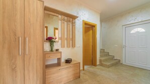 A wooden wardrobe with a mirror, a small desk with drawers, and a vase of flowers. - Villa Sunny Hill (Budva)