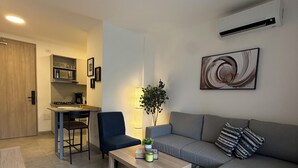 Un salon moderne avec un canapé gris, une table basse et un coin repas comprenant une chaise et une petite table.