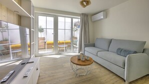 A modern living room with a grey sofa, a wooden coffee table, and a TV on a white cabinet. - L'instant Bassin - Air Conditionné et proche plage d'Arcachon (Arcachon)