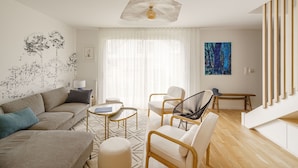 A modern living room with a sofa, chairs, a coffee table, and a unique ceiling light fixture. - Ti Armor - Maison à 200m de la plage (Benodet)
