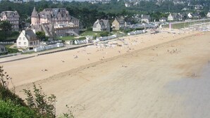 Une plage bordée d’une rangée de maisons, avec une église en arrière-plan.