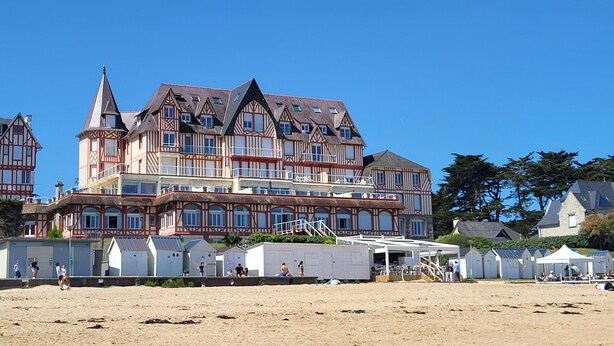 Un grand immeuble à étages, de style architectural traditionnel, doté d’un balcon et d’une zone couverte accessible par un escalier.