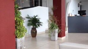 A spacious lobby with a modern design, featuring a reception desk, potted plants, and a tiled floor. - Terra do Mar (San Bernardo del Tuyú)