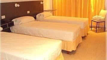 Una habitación de hotel con dos camas individuales, una mesita de noche, una silla y una cortina.