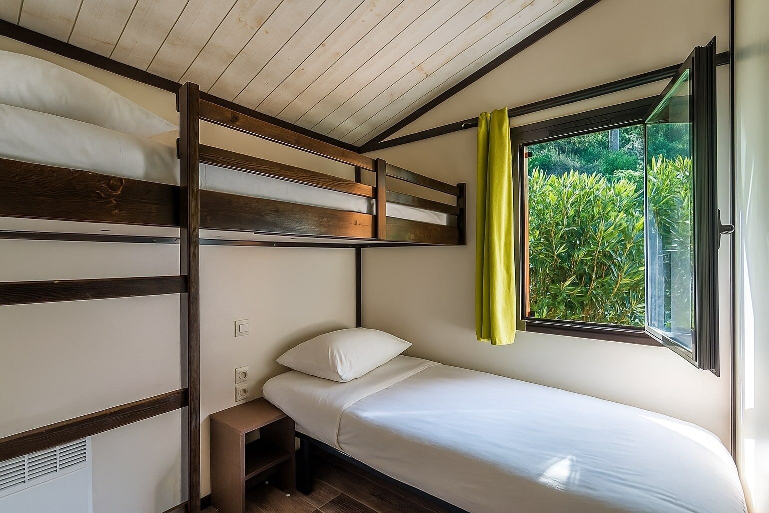 Una litera con una cama individual abajo, un estante pequeño y una ventana con cortinas.