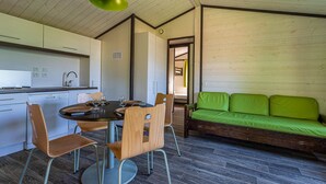 A modern kitchen with a dining area, a green sofa, and a wooden floor.