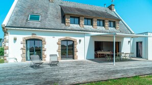 A two-story house with a covered patio, stone arch windows, and a dining area visible through the open door. - Ti Ar Mor Braz- Maison avec grand jardin (Saint-Philibert)