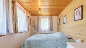 A bedroom with a bed, wooden ceiling, curtains, and framed pictures on the wall. - Chalet des cimes - Avec jardin (La Bresse)