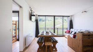 Un comedor con una mesa de madera preparada para cuatro personas, bancos y un sofá con cojines.