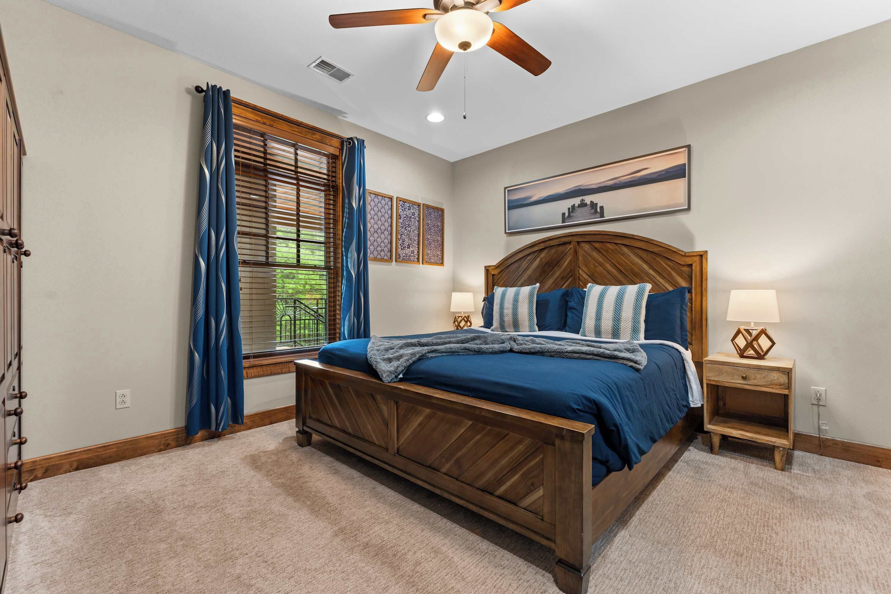 A bedroom with a wooden bed, a nightstand, a ceiling fan, and a window with curtains.