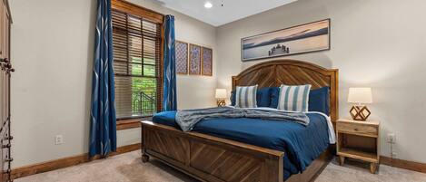 A bedroom with a wooden bed, a nightstand, a ceiling fan, and a window with curtains.