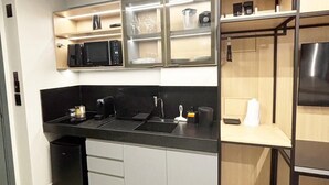 Cozinha moderna com bancada preta, eletrodomésticos de aço inoxidável e micro-ondas embutido.