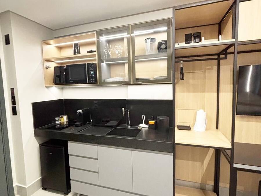 Cozinha moderna com bancada preta, eletrodomésticos de aço inoxidável e micro-ondas embutido.