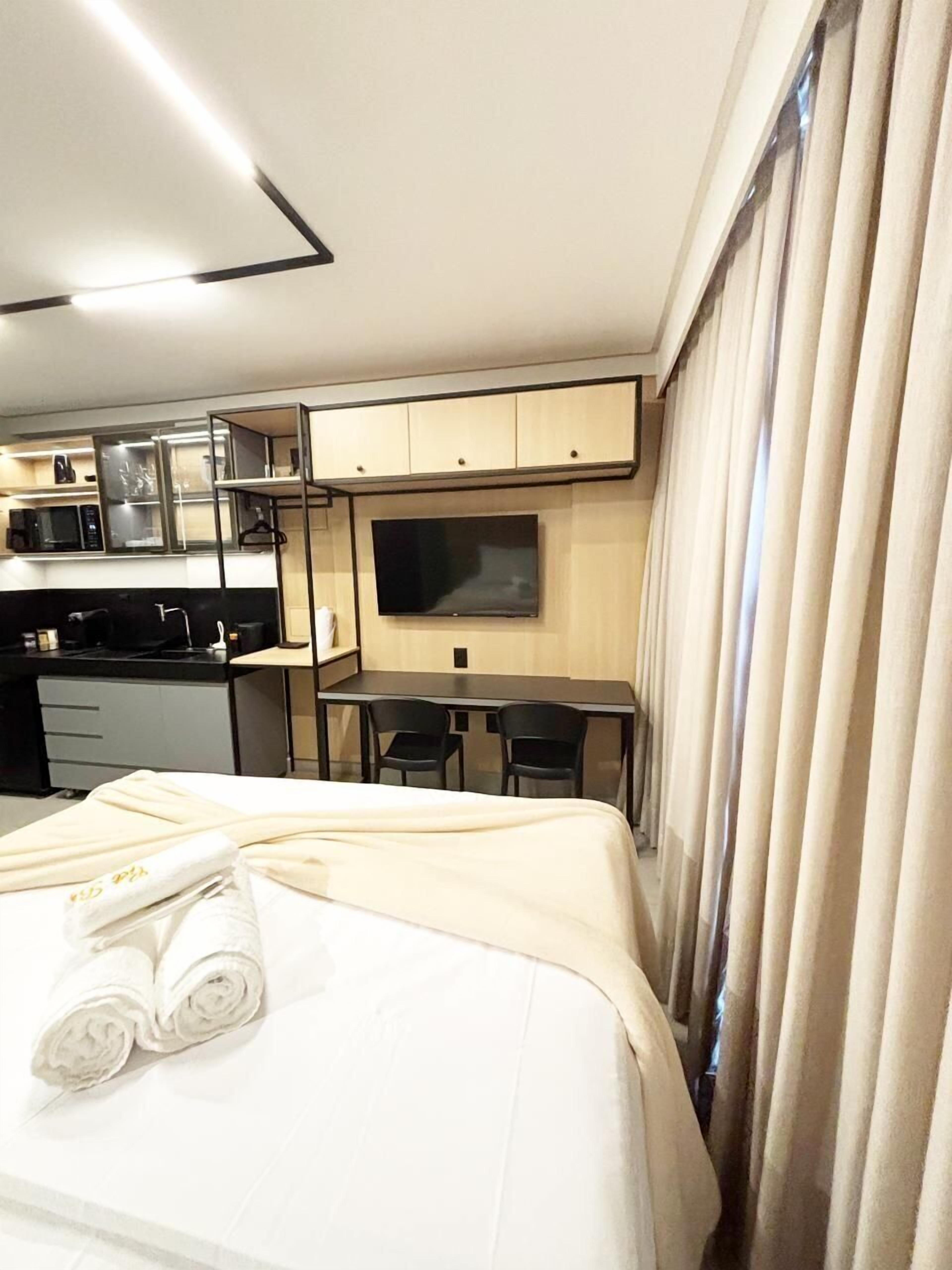 Ein Hotelzimmer mit Bett, Schreibtisch, Fernseher und einer Küchenzeile.