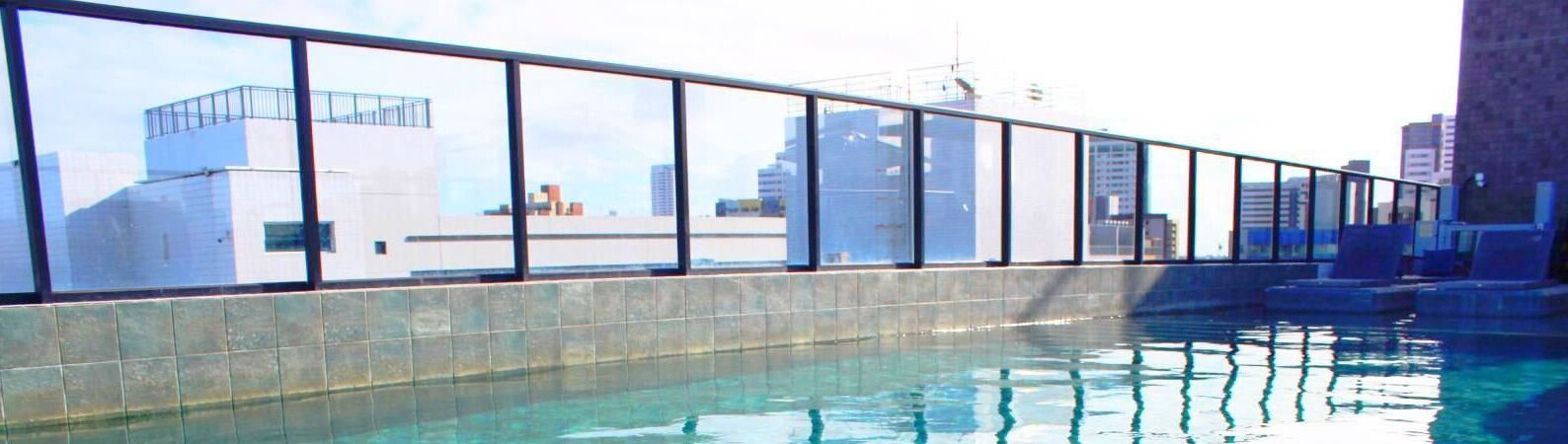 Una piscina interior con vistas a la ciudad a través de amplios ventanales.