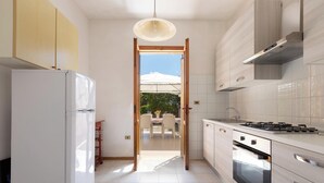Una cocina moderna con refrigerador, estufa, horno y vistas a un patio exterior.