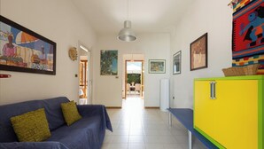 Un pasillo con un sofá azul, un mueble amarillo y varias obras de arte enmarcadas en las paredes.