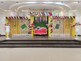 Un escenario con un sofá rojo, decoraciones florales y un fondo verde.