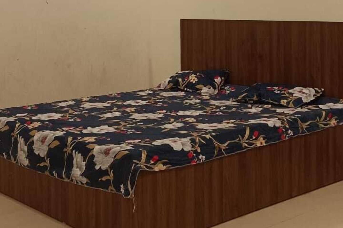 A bedroom with a wooden headboard, a bed with floral bedding, a ceiling fan, and a wall-mounted light.