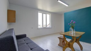 A modern living room with a grey sofa, a wooden coffee table, and a window with natural light. - Chastnyy Sektor (Bosteri)